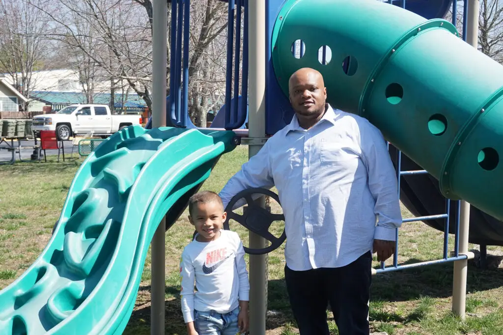 A father and young child at a playground slide